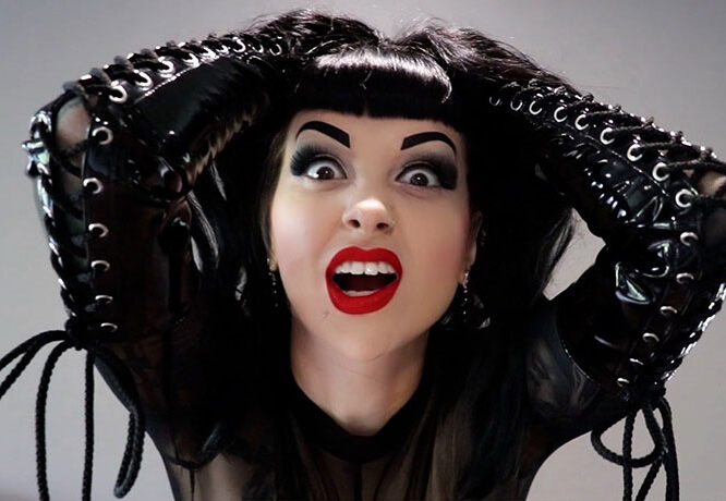 Lady Vi, wearing black PVC gloves, screams in frustration while pulling her hair.